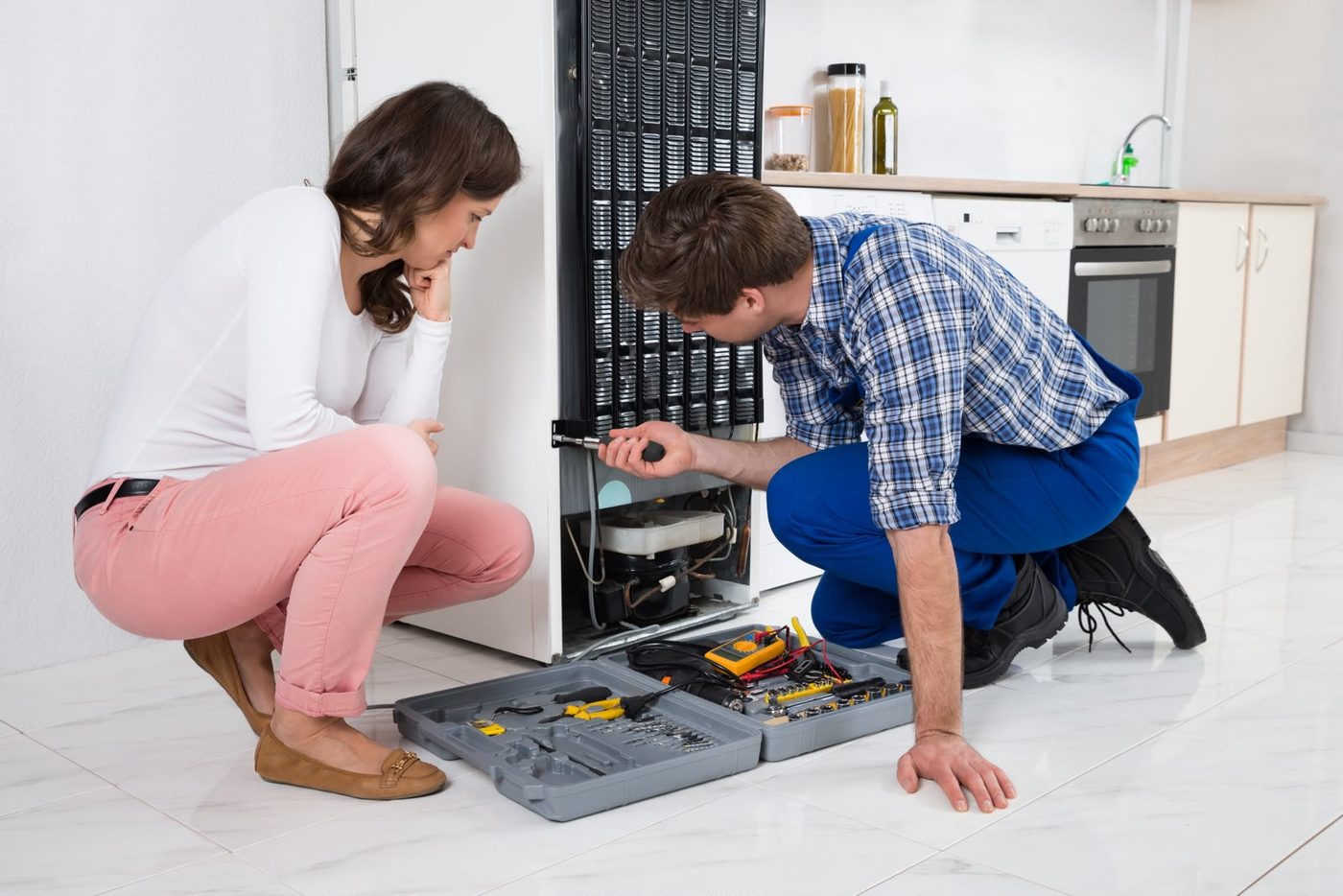 Technician explaining a repair to a customer in their kitchen